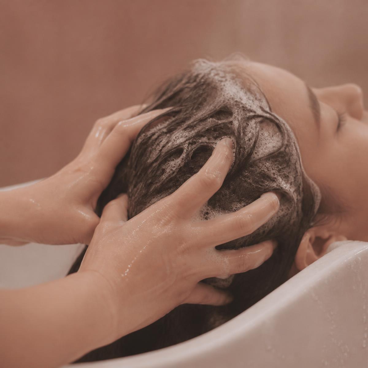 Mains massant un cuir chevelu couvert de mousse